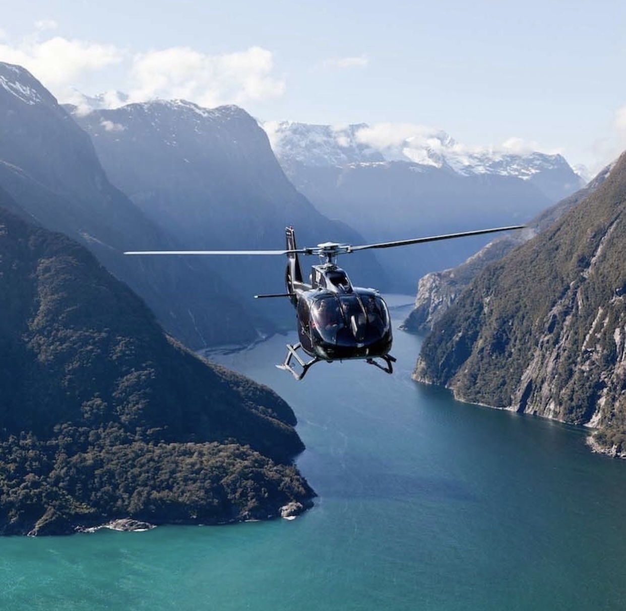 Private helicopter flying over a Norwegian fjord at golden hour